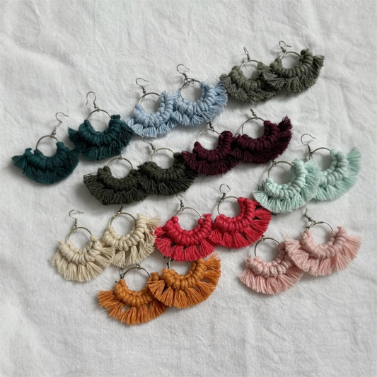 Colorful macrame earrings arranged on a textured white surface